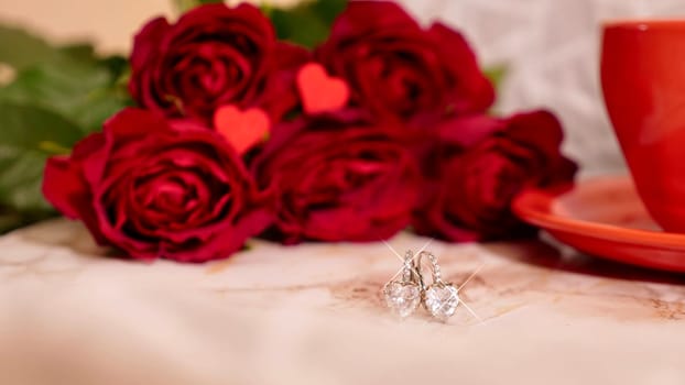 Background Festive Flatlay, composition for Valentine's Day on February 14. Coffee in a red cup, red rose flowers and diamond heart earrings