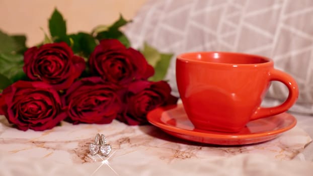 Background Festive Flatlay, composition for Valentine's Day on February 14. Coffee in a red cup, red rose flowers and diamond heart earrings