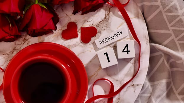 Festive Flatlay, composition for Valentine's Day on February 14. Coffee in a red cup and red rose flowers at home in bed