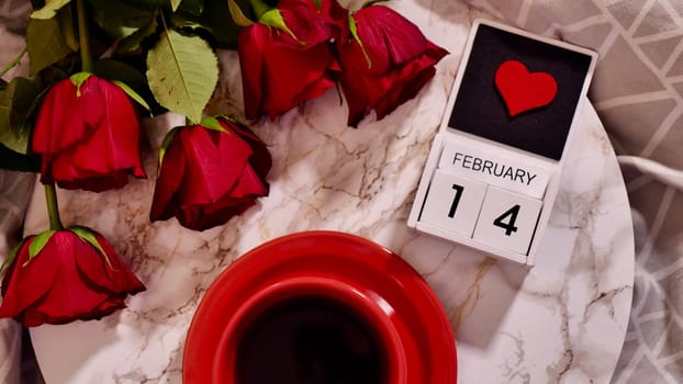 Festive Flatlay, composition for Valentine's Day on February 14. Coffee in a red cup and red rose flowers at home in bed