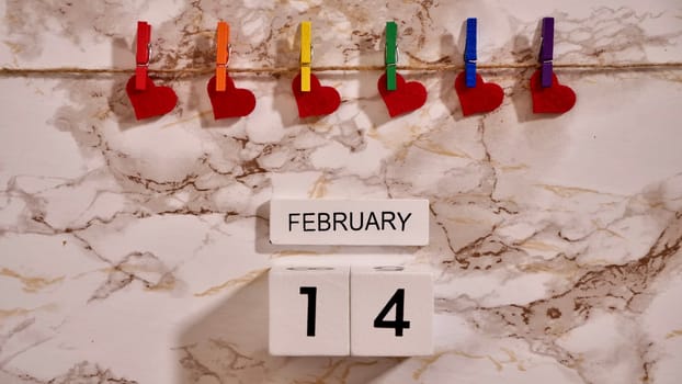 Happy Valentines Day LGBTQIA, colored rainbow clothespins with red hearts and text, on marble background close up.