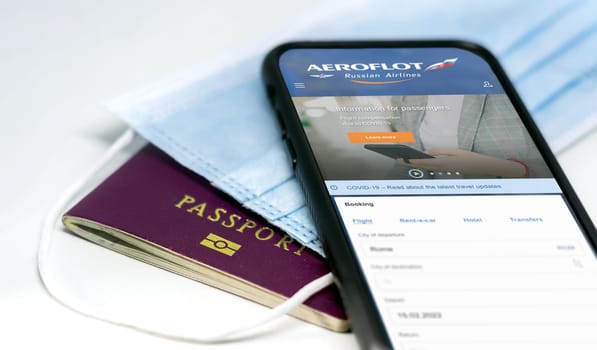 Moscow, Russia, July 2021: phone with the Aeroflot Russian airlines app on the screen lying over a protective mask and a passport. Travel safety and restrictions during coronavirus pandemic