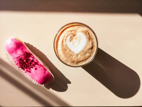 Pink eclair and a glass of cappuccino on a beige background in bright light with hard shadows.