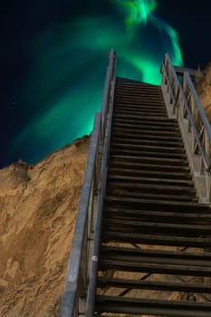 Treppe von Richtung Strand im Hintergrnd der Nachtsternenhimmel, mit Nordlichtern, kosmischer Raum