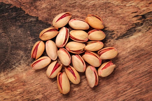 Tabletop view - turkish red roasted pistachios on wooden board.
