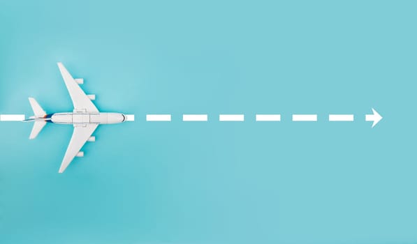 Conceptual with Toy Plane and white arrow isolated over bright blue background