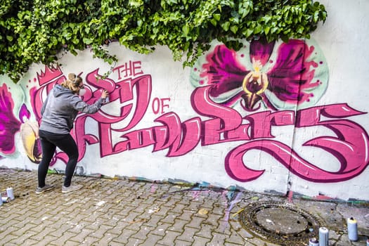 WETZLAR, GERMANY - 23.05.2021: Young female Artist doing artificial typography colorful graffiti senic on house facade in WETZLAR GERMANY