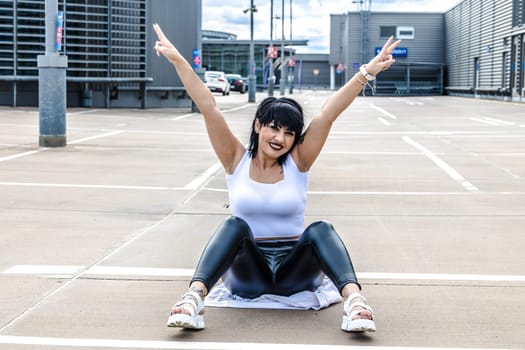 Young woman sitting on the floor and stretching out arms
