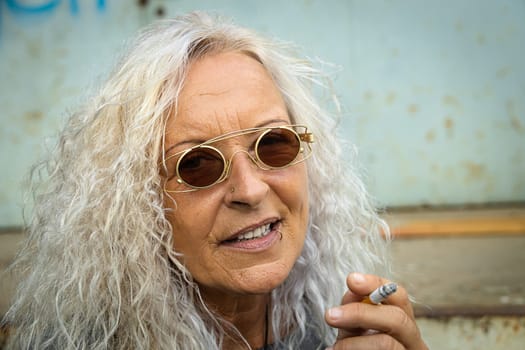 Beautiful woman with long bright curly hair is smoking a cigarette.