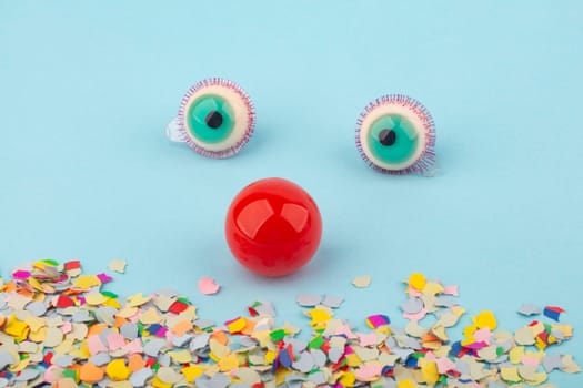 Red Nose with confetti over light blue background. Conceptual Photo to use for all funny celebration themes.