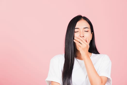 Portrait Asian beautiful young woman emotions tired and sleepy her yawning covering mouth open by hand, studio shot isolated on pink background, Thai female insomnia concept