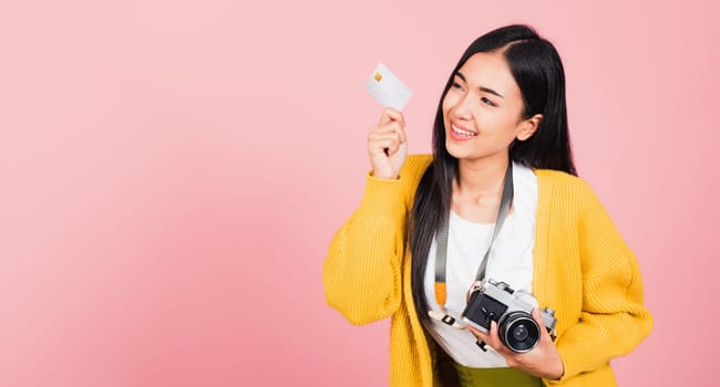 Happy Asian portrait beautiful young woman excited smiling photographer holding credit credit card bank and retro vintage photo camera ready travel isolated on pink background, tourism and vacation