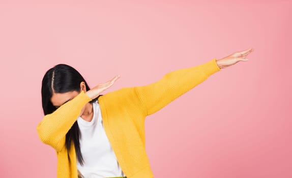 Asian happy portrait beautiful cute young woman teen smile standing move showing DAB dance against gesture raise hands arms covering  face isolated, studio shot on pink background with copy space