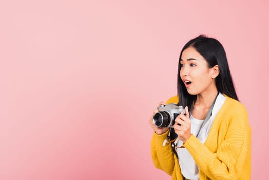 Attractive happy Asian portrait lifestyle beautiful young woman excited smiling photographer holding retro vintage photo camera ready to shoot isolated on pink background, tourism and vacation concept