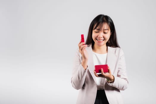 Smiling woman confidence opening a red gift box on palm isolated white background, surprise birthday or Christmas day and valentine, Asian happy portrait beautiful young female studio shot, copy space