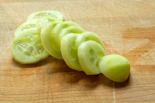 Peeled and sliced cucumber on a wooden board, close up