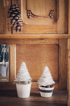 Two mini DIY paper trees Christmas decoration with natural moss on wooden cupboard