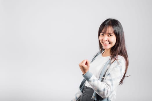 Smiling happy woman makes raised fists up celebrating her winning success gesture, Happy Asian beautiful young female excited say yes, studio shot isolated on white background with copy space