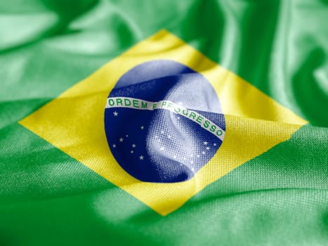 Close up of the national flag of Brazil on a ruffled fabric. Curves and folds of the satin fabric with texture. Selective focus and depth of field. Democracy and politics. South american country.