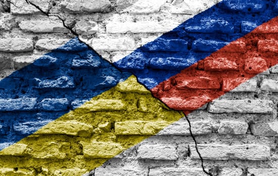 the flags of Ukraine and Russia painted on a ruined bricked wall and divided by a diagonal crack. International diplomatic relations.