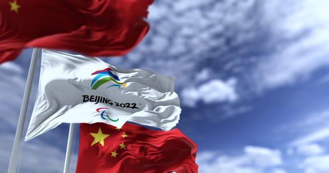 Beijing, China, February 2022: The flag of Beijing 2022 Paralympics waving in the wind with the national flags of China. Winter paralympics games are scheduled to take place from 4 to 13 march 2022