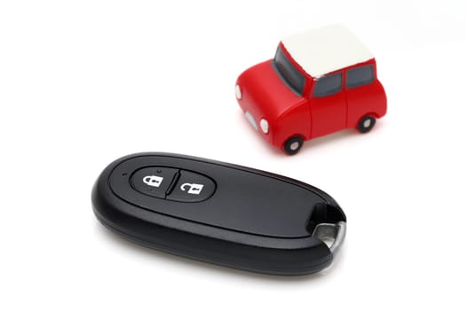 car black key remote controller and small toy car on white background