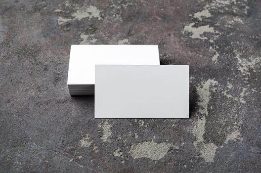 Blank business cards on concrete background. Mockup for branding identity. Studio shot.