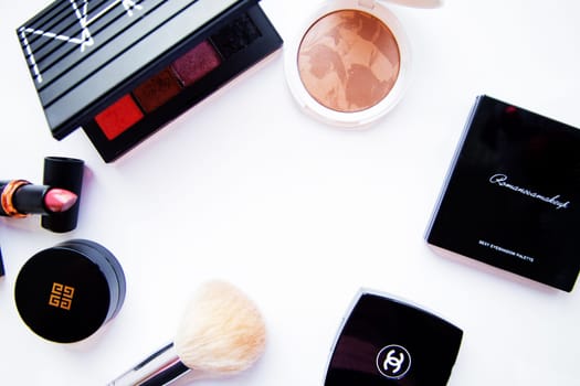 Moscow, 2021. White powder and bronzer, packages with eye shadow, lipstick, blush and a brush of different brand brands lie on a white background around with a place for text. High quality photo