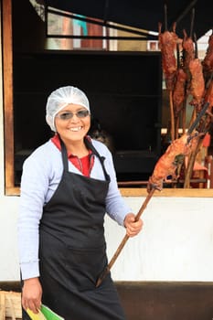 Woman with fresh roasted Guinea Pig in Lamay. Peru