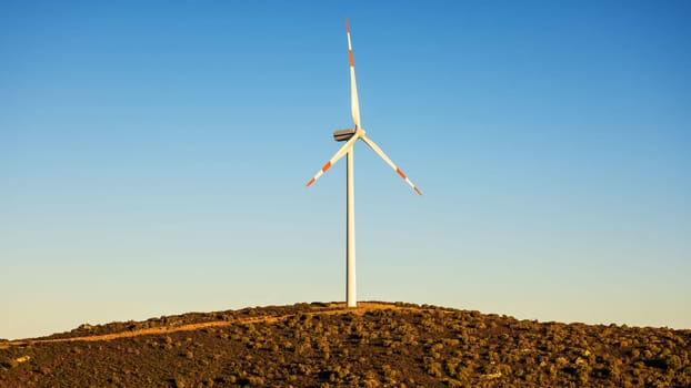 Wind turbines on a beautiful sunset sky in a mountain wind farm in Sardinia. Renewable energy concept, green energy generation. Energy industry.