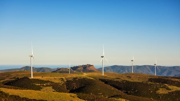 Wind turbines on a beautiful sunset sky in a mountain wind farm in Sardinia. Renewable energy concept, green energy generation. Energy industry.