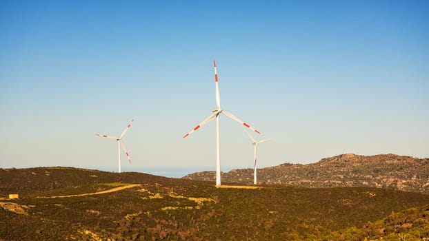 Wind turbines on a beautiful sunset sky in a mountain wind farm in Sardinia. Renewable energy concept, green energy generation. Energy industry.
