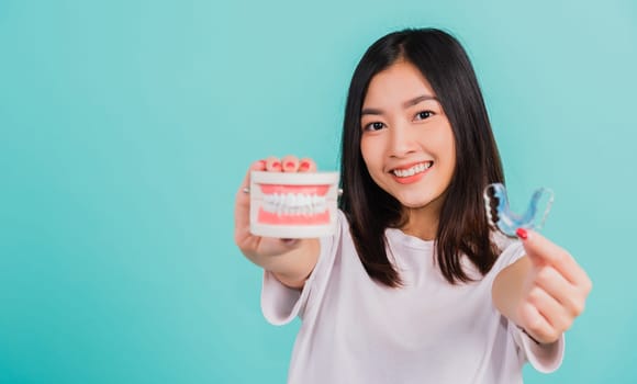 Portrait young Asian beautiful woman smiling holding silicone orthodontic retainers for teeth retaining tools after removable braces, Female hold model teeth before, Orthodontics dental healthy care