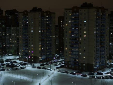 St. Petersburg snow-covered city at night in winter, lights are on in the windows, lonely passers-by rush home