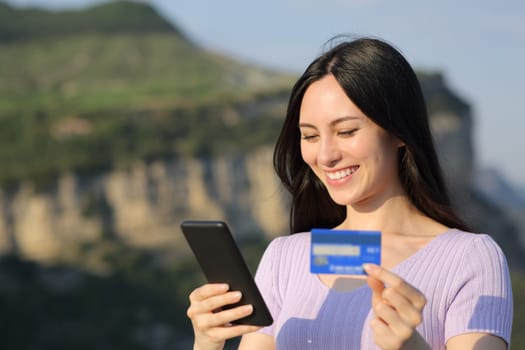 Asian woman buying online with credit card in nature