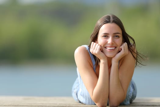 Happy woman looking at camera lying on pier