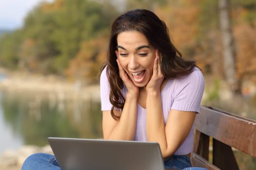 Surprised woman checking laptop in a lake on vacation