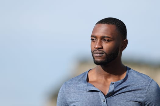 Serious man with black skin contemplating outdoors