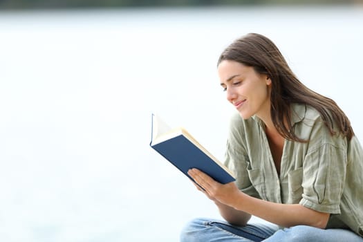 Happy woman reading a book in a lake