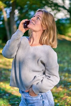 Beautiful woman talking on the phone in the park in summer. High quality photo