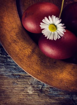 Red easter eggs in rustic wooden plate