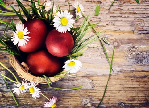 Red easter eggs in basket with flowers