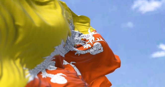 Detail of the national flag of Bhutan waving in the wind on a clear day. Bhutan is a landlocked country in the Eastern Himalayas. Selective focus.