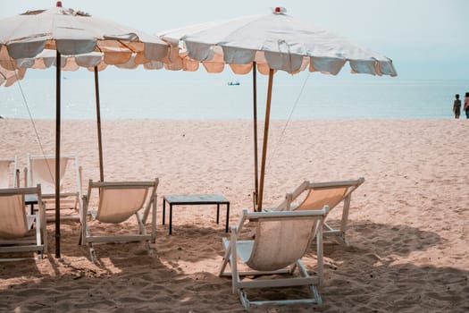 Deckchairs And white Parasol In The Tropical Beach. white umbrella on the beach in summer