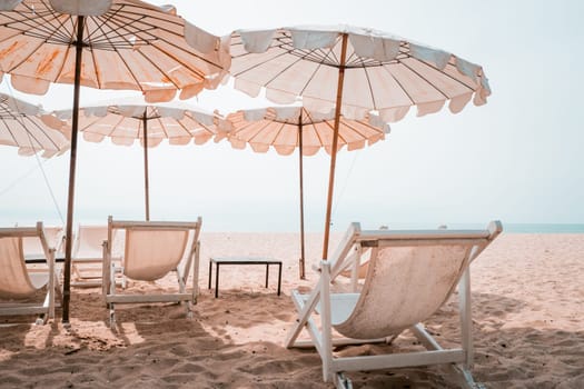 Deckchairs And white Parasol In The Tropical Beach. white umbrella on the beach in summer