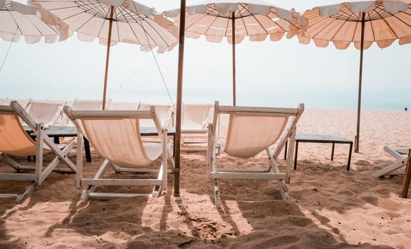 Deckchairs And white Parasol In The Tropical Beach. white umbrella on the beach in summer