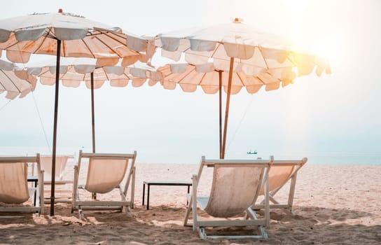 Deckchairs And white Parasol In The Tropical Beach. white umbrella on the beach in summer