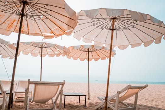 Deckchairs And white Parasol In The Tropical Beach. white umbrella on the beach in summer