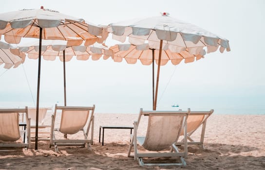 Deckchairs And white Parasol In The Tropical Beach. white umbrella on the beach in summer