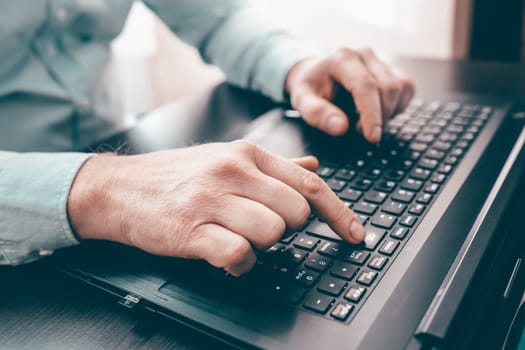 Close up of business man hand working on laptop computer on wooden desk as concept